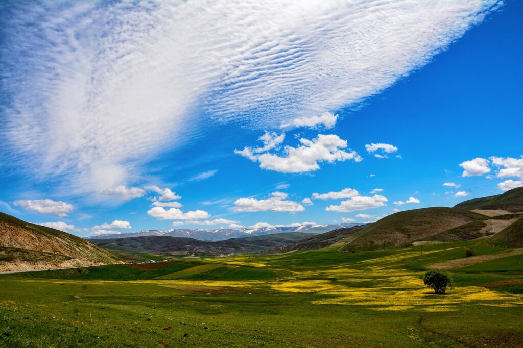 Open countryside with sky, clouds and a small community in the distance.