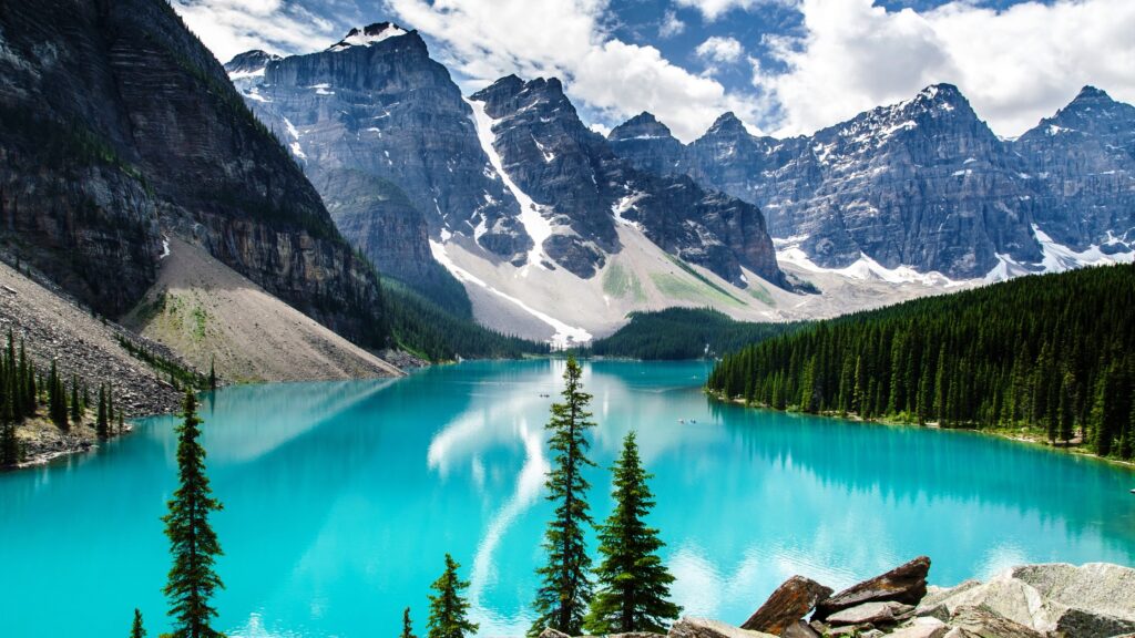 Crystal blue water in a mountain lake with mountains towering over the landscape in the distance